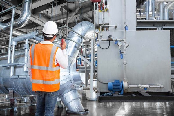 Engineer working in a thermal power plant with talking on the walkie-talkie for controlling work